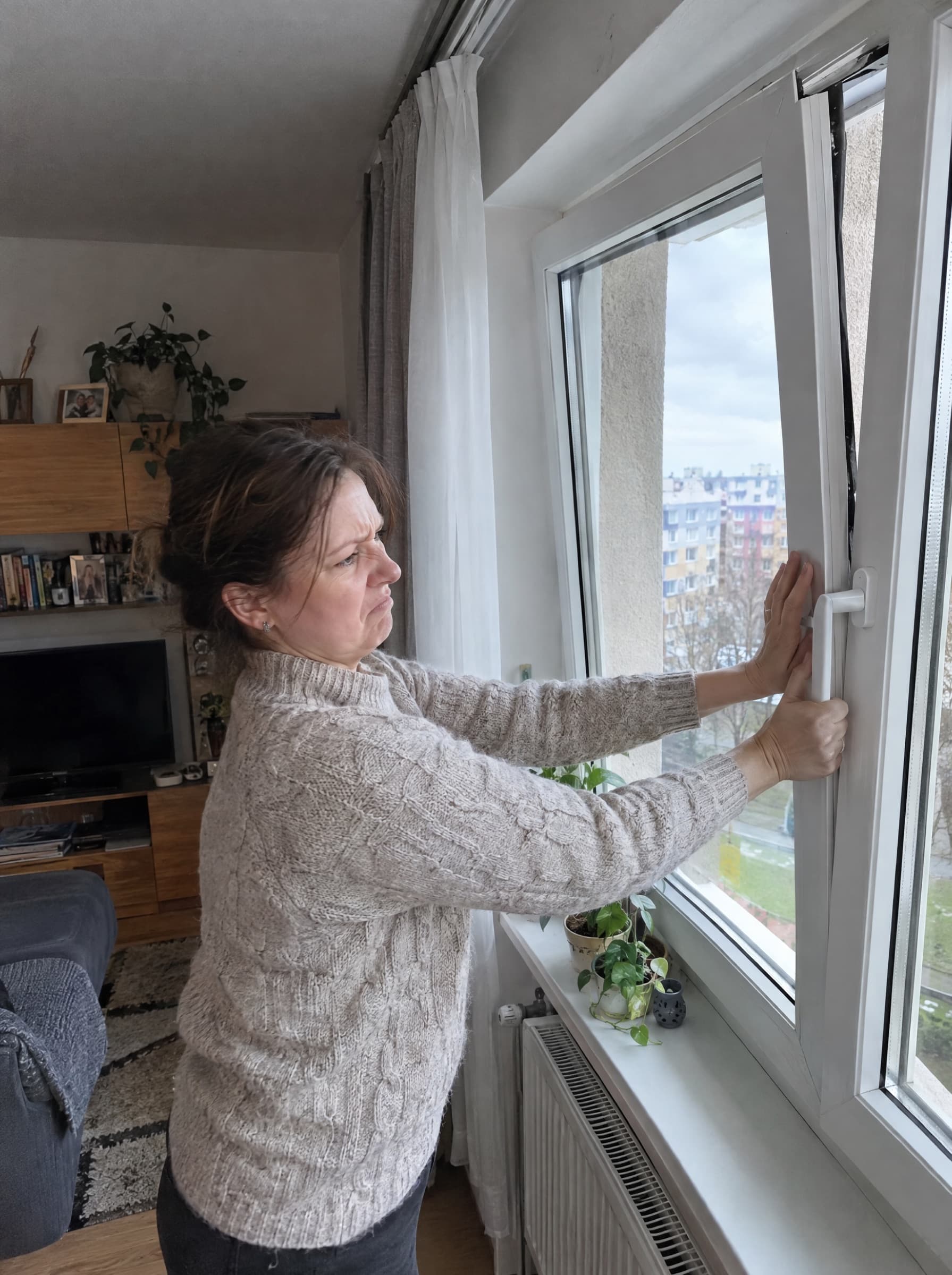 Žena se snaží zavřít okno, které nedoléhá